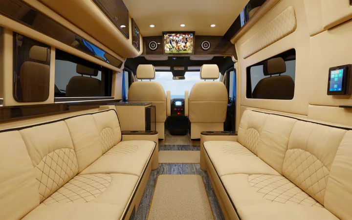 Luxurious RV rental interior features cream quilted seating, a large TV for entertainment, and a spacious, comfortable design.. Ultimate Toys Ultimate Camper 2023