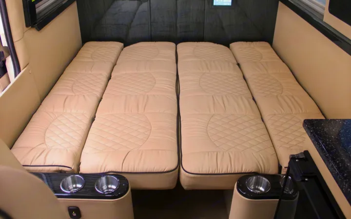 RV rental interior: Flexible sleeping with four cream quilted mattresses, dark piping, and integrated cupholders.. Ultimate Toys Ultimate Camper 2023