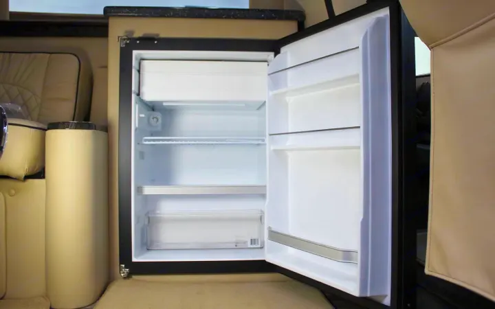 Empty mini-fridge in an rv rental, showing spacious shelves & freezer. Ready for your trip's provisions.. Ultimate Toys Ultimate Camper 2023