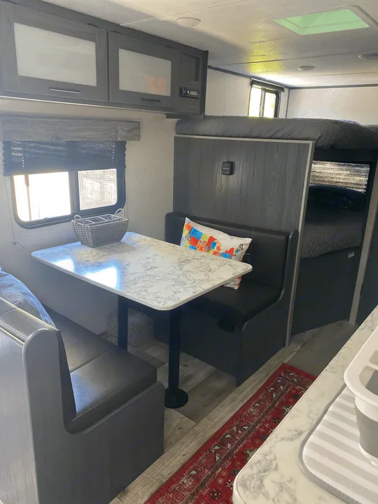 Comfortable rv rental interior: dining area with booth seating, overhead cabinets, and bunk beds visible.. Dutchmen Other 2021