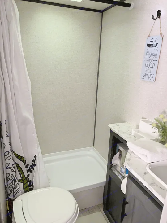 This RV rental bathroom features a compact shower, toilet, vanity, and a humorous 'no pooping' sign on the wall.. Dutchmen Other 2021