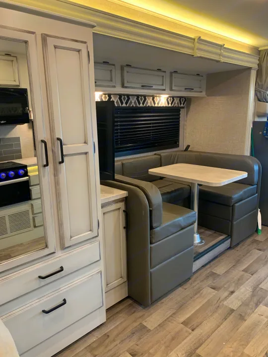 Cozy RV rental: gray dinette, kitchen, and white cabinets. Perfect for comfortable mobile living.. Entegra Odyssey 2022
