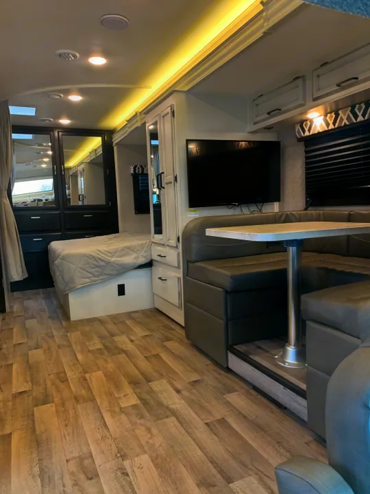 Explore this RV rental's modern interior. Includes a comfortable bed, U-shaped dinette, and TV, perfect for your journey.. Entegra Odyssey 2022