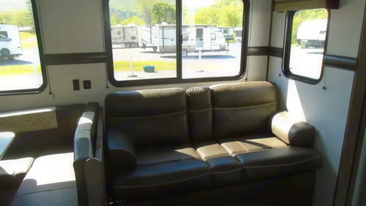 RV rental living space: comfy sofa, dinette, and large windows with outdoor views of other RVs.. Crossroads RV Zinger 2022