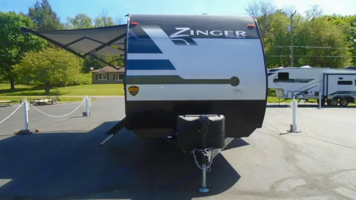 Front view of a black, white, and blue Zinger travel trailer RV rental with its awning extended.. Crossroads RV Zinger 2022