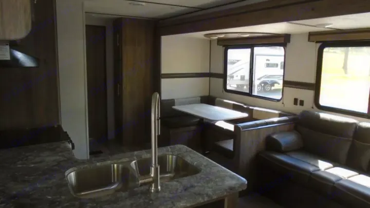 RV rental interior: A modern kitchen with a double sink, dinette booth, and dark leather sofa create a comfortable living space.. Crossroads RV Zinger 2022
