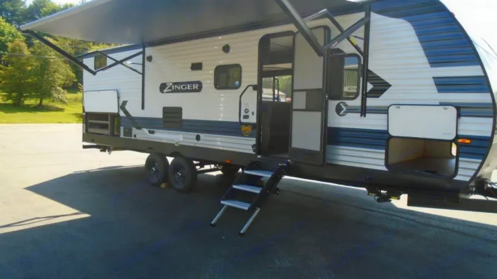 A white & blue Zinger travel trailer with an extended awning, open door, and steps, ideal for rv rental adventures.. Crossroads RV Zinger 2022
