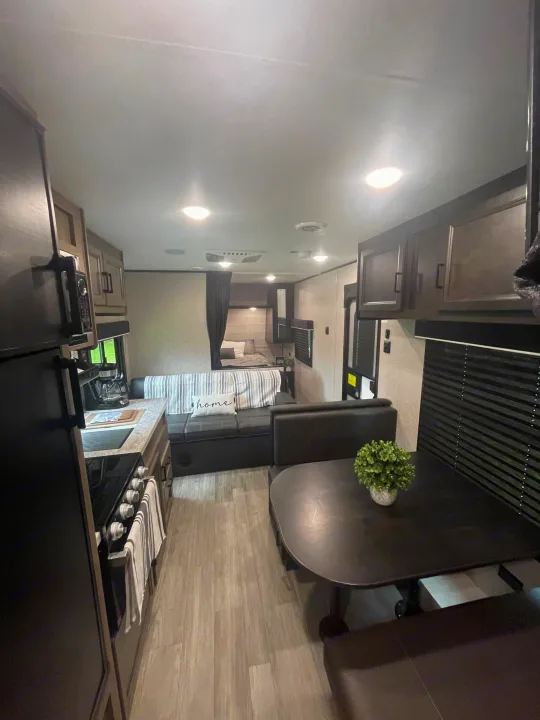 Spacious RV rental interior featuring a full kitchen, dining booth, and convertible sofa bed, ready for your next adventure.. Jayco Jay Flight 2022