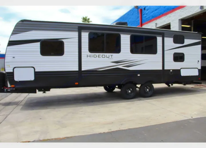 A white and black 'Hideout' travel trailer on concrete. Ideal for an RV rental, ready for your next outdoor adventure.. Keystone RV Hideout Luxury 2021