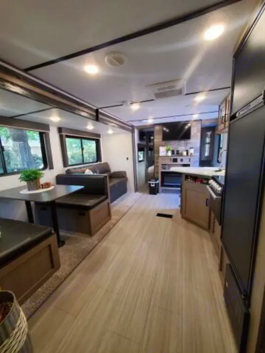 Spacious RV rental interior featuring a bright kitchen, dining booth, and cozy living area with fireplace and TV.. Keystone RV Hideout Luxury 2021