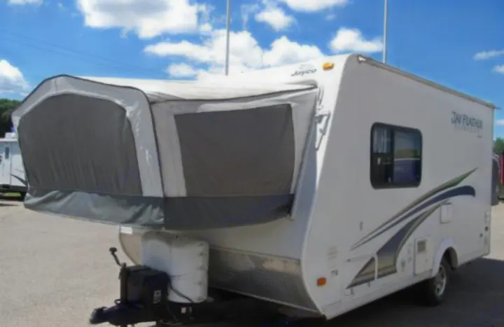 White Jayco Jay Feather hybrid travel trailer, ideal for rv rental trips. Features a pop-out tent section.. Jayco Jay Feather Ultra Lite 2012