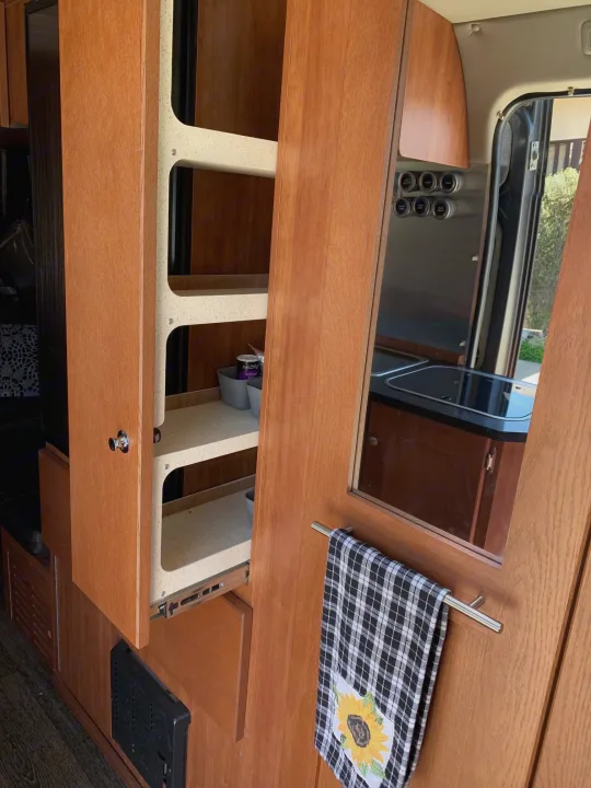 RV rental interior: Pull-out pantry for efficient storage, with mirrored door reflecting a compact kitchen space.. Roadtrek Roadtrek Class B 2018
