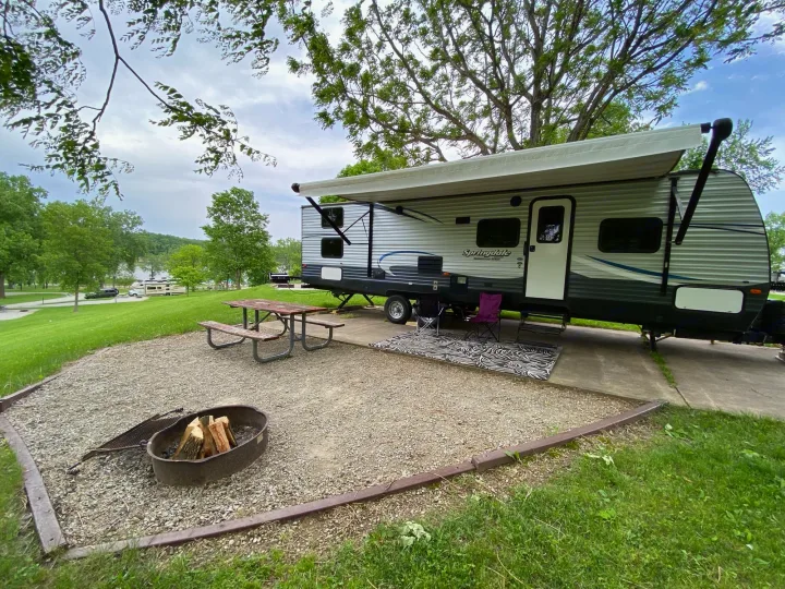 Scenic RV rental campsite with a cozy travel trailer, extended awning, picnic table, and fire pit.. Keystone RV Summerland 2018