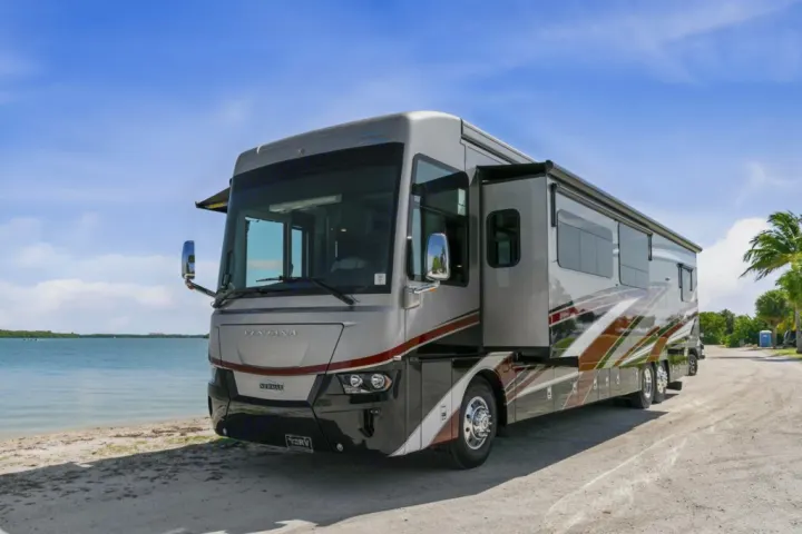 Spacious RV rental, a luxury motorhome parked on a sandy beach next to calm water, ready for adventure.. Ventana Ventana Motorhome 2022