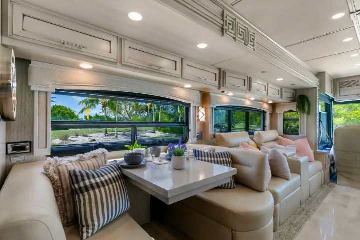 Luxurious RV rental interior, showcasing a bright dining area, comfortable seating, and scenic views through large windows.. Ventana Ventana Motorhome 2022