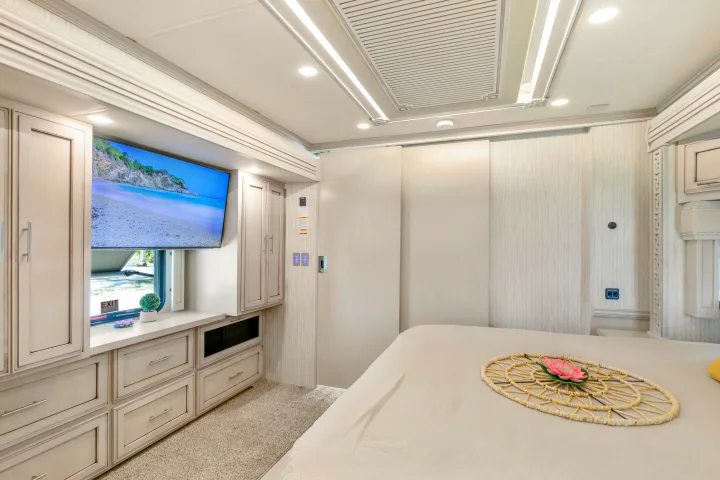 Spacious luxury RV rental bedroom with modern design, built-in TV, ample storage, and comfy bed for travel.. Ventana Ventana Motorhome 2022