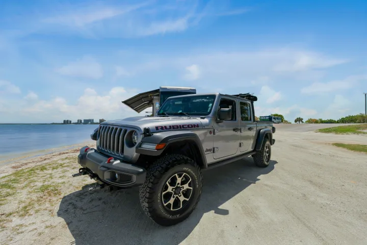A rugged silver Jeep Gladiator parked by the water, next to an RV, ready for an adventure or RV rental trip.. Ventana Ventana Motorhome 2022