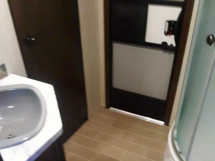 Inside this RV rental's compact bathroom, featuring a vanity sink, curved shower, and a door with a frosted privacy panel.. Forest River Cherokee Grey Wolf 2020