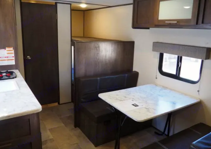 Explore this RV rental's interior: a kitchen counter, cozy dinette, window with shade, cabinets, and bunk beds.. Coleman Coleman Lantern 2022