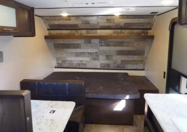 RV rental interior: A cozy dinette converts to a bed, featuring a plank wall, light counters, and dark seating.. Coleman Coleman Lantern 2022