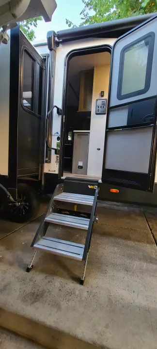 Open door on an RV rental with extended steps, showing interior controls & storage. Get ready for your next camper adventure!. Keystone RV Outback 2021