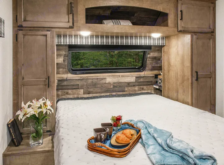 Cozy RV rental bedroom with breakfast in bed setup, wood paneling, and ample storage for comfortable travel.. Venture Stratus VBH261 2022
