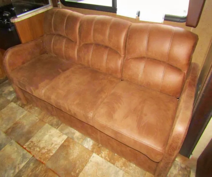 Brown faux leather sofa in an RV rental. Provides comfortable seating for your travels.. Coachmen Leprechaun 2017