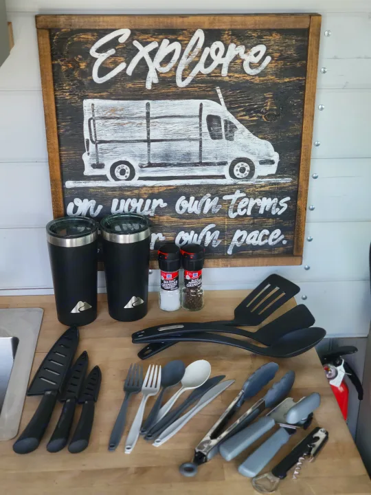 RV rental kitchen essentials: utensils, mugs, spices, and an "Explore" sign, ready for your adventures.. Ram Promaster 2020