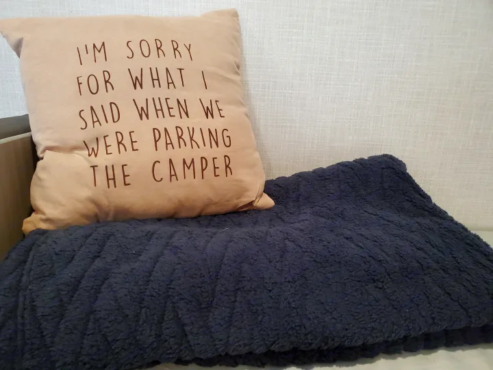 Cozy interior of an RV rental featuring a humorous pillow: "I'm sorry for what I said when we were parking the camper.". Coleman LANTERN LT 17B 2022