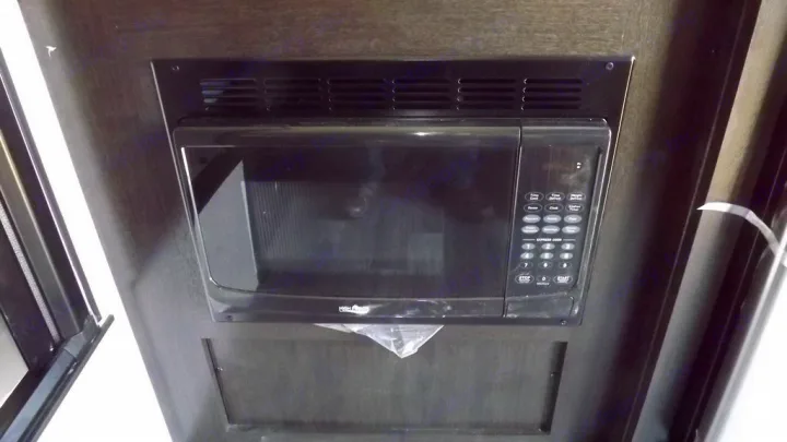 Black built-in microwave oven mounted in dark cabinetry, seen inside an RV rental.. Braxton Creek Bushwhacker 2022