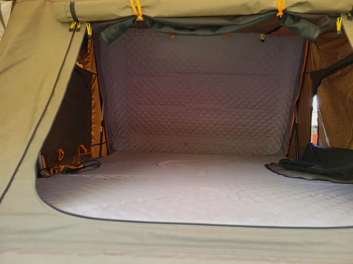 Comfortable interior of an RV rental rooftop tent, featuring a quilted mattress and walls for a cozy sleep.. Toyota Tundra 2011