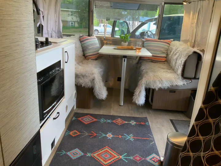 This RV rental offers a cozy dinette with food & drink, a compact kitchen, and inviting decor for travel.. Airstream Airstream 2020