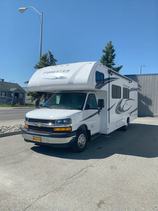 A white Forester Class C RV rental, parked on asphalt under a blue sky in Alaska.. Forest River Forester 2551DSLE 2021
