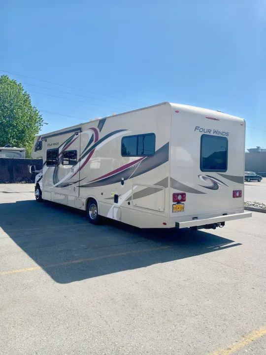 Beige Four Winds RV rental, parked in a lot under a clear sky, ready for your next travel adventure.. Thor Motor Coach Four Winds 2019