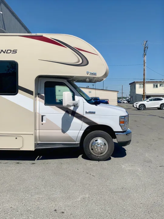 A beige Class C Thor rv rental, on a Ford E-450 chassis, parked outdoors on a sunny day.. Thor Motor Coach Four Winds 2019