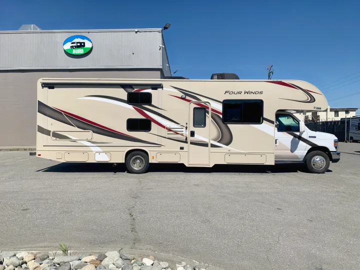 A cream-colored Thor Four Winds RV rental parked at Alaska RV Rentals under a clear sky, ready for adventure.. Thor Motor Coach Four Winds 2019