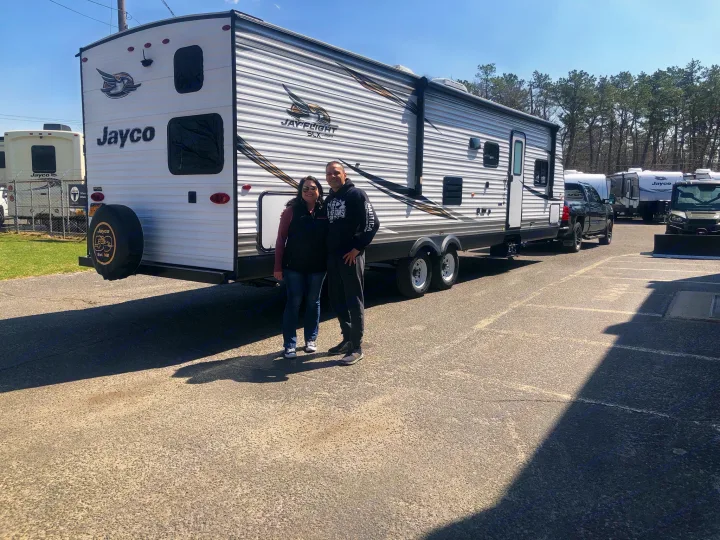 Happy couple with their Jayco travel trailer, ideal for future trips or an rv rental.. Jayco Flight 2019