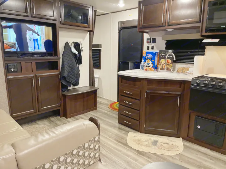 An inviting rv rental interior showing a kitchen counter with snacks, a comfy couch, and TV. Ideal for travel.. Jayco Flight 2019