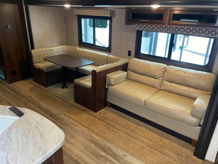 Comfortable rv rental interior with a light leather sofa, U-shaped dinette, and overhead storage. Ideal for road trips!. Jayco Flight 2019