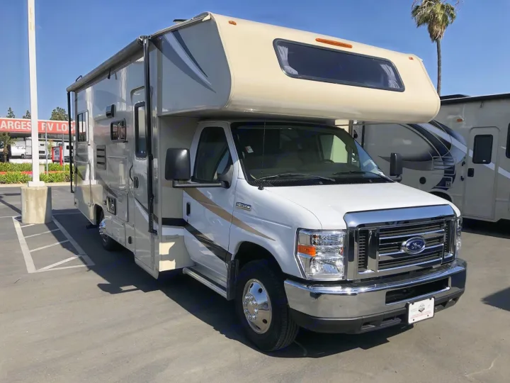 Modern white and tan Class C Ford E-350 RV rental, parked outdoors on a sunny day. Ready for your next adventure.. Coachmen Leprechaun 2022