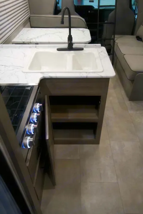 This RV rental's kitchen features a bright double sink, stove, stylish marble-look counters, and practical storage solutions.. Freelander 27QB 2022