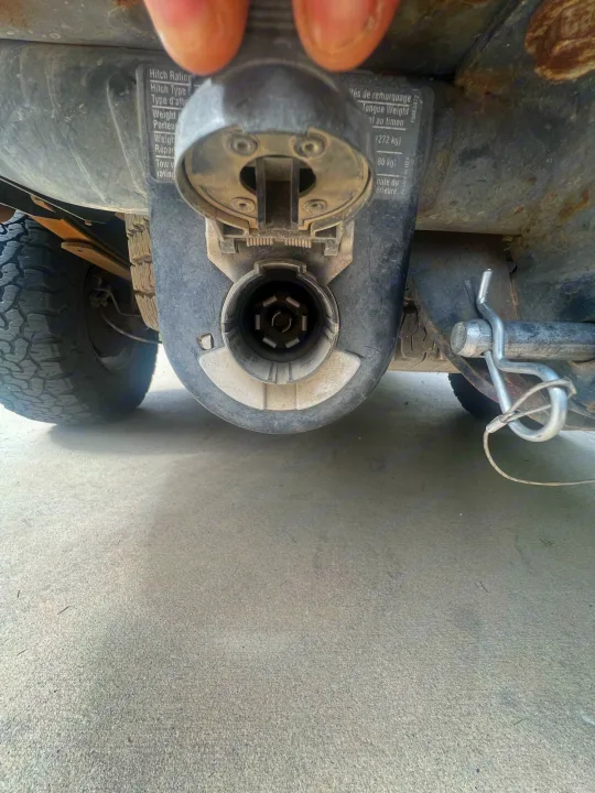 Close-up of a vehicle's trailer hitch, showing a 7-pin electrical connector and weight ratings for RV rental towing.. Dutchmen Coleman Expedition LT 2013