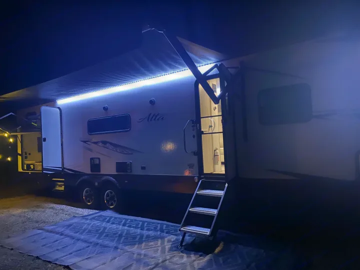 This RV rental shines at night with vibrant blue awning lights and an inviting open door, ready for adventure.. Forest River Other 2022