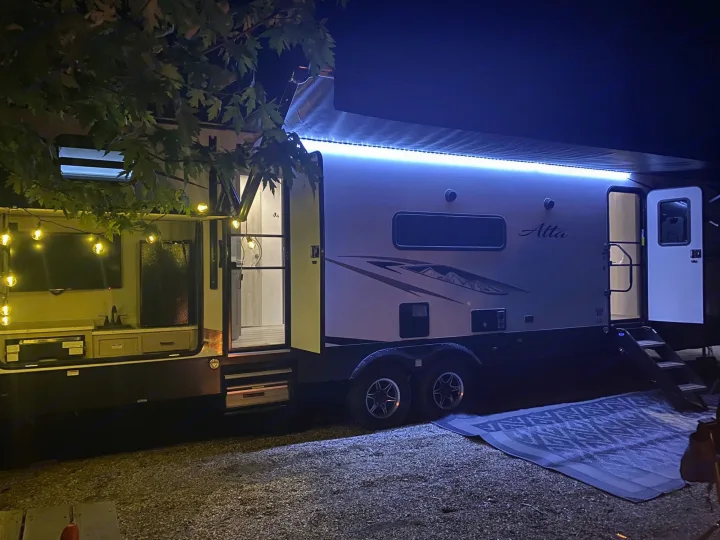 Experience an inviting rv rental at night, featuring blue awning LEDs and warm string lights, perfect for outdoor living.. Forest River Other 2022
