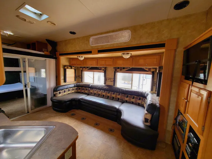 Inviting RV rental living area with a large U-shaped sofa, kitchen sink, and bunk access. Cozy and functional.. Heartland Cyclone 2009