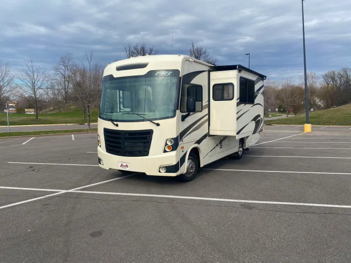 A large, white Forest River FR3 Class A motorhome RV rental is parked with its side slide-out extended.. Forest River 23DS 2018