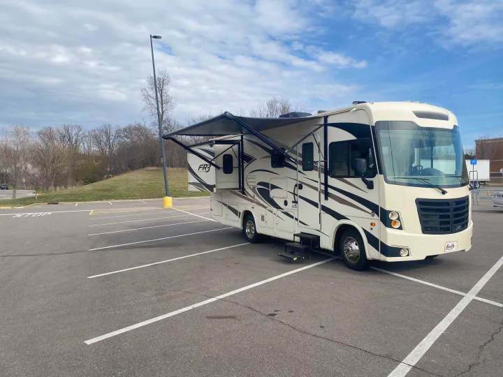 Spacious Class A RV rental parked with awning and slide-out extended in a parking lot on a cloudy day.. Forest River 23DS 2018