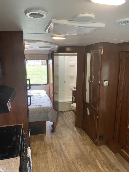 Step inside this RV rental showcasing a compact kitchen, comfortable bedroom, and functional bathroom off the central hallway.. Forest River 23DS 2018