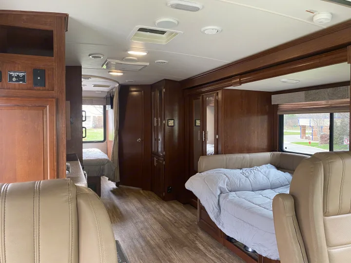 RV rental interior: detailed view of dark wood cabinetry, vinyl plank flooring, and light seating areas with bedroom & pull-out bed.. Forest River 23DS 2018