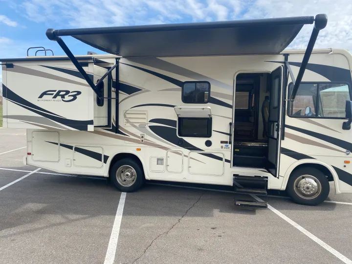 Forest River FR3 Class A motorhome RV rental, showing an extended awning, open door, and outdoor entertainment.. Forest River 23DS 2018